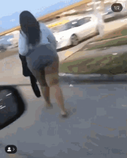 a woman is walking down a sidewalk with a car in the background and a 1/2 icon on the bottom right