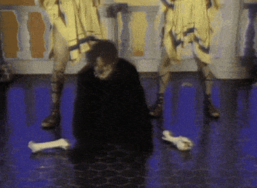 a man is kneeling on the floor with bones on the floor in front of him
