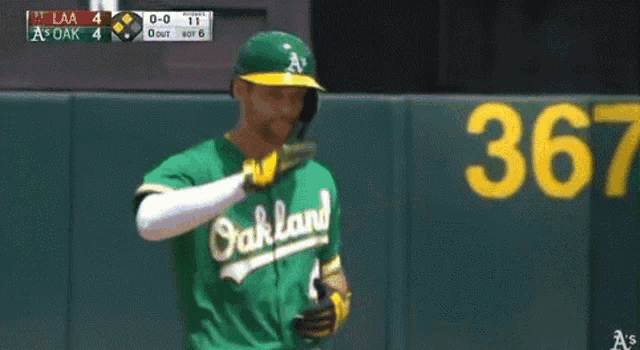 a baseball player for the oakland a's looks at his phone