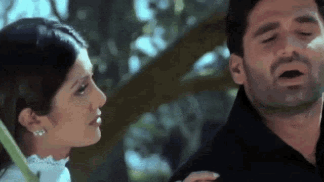 a man and a woman are standing next to each other and the woman is looking at the man 's face