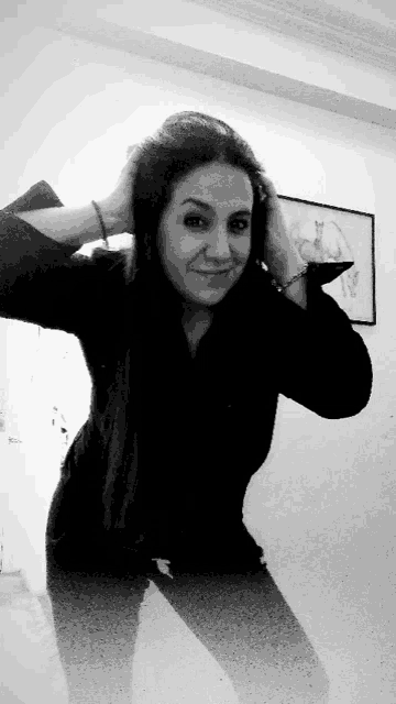 a black and white photo of a woman with her hands on her hair