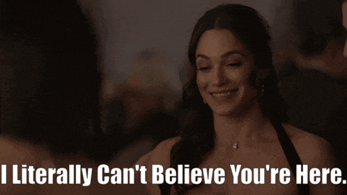a woman in a black dress is smiling with the words " i literally can 't believe you 're here " below her