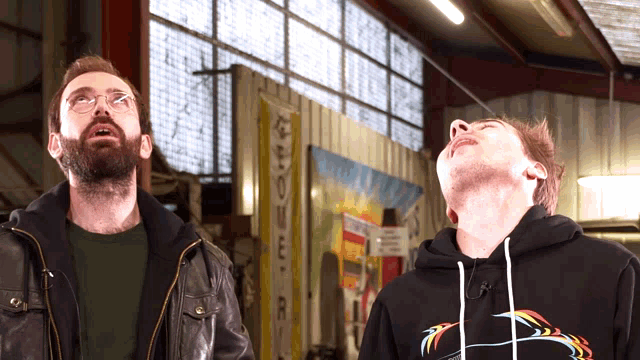 two men are looking up in a room with a sign that says ' a & r ' on it