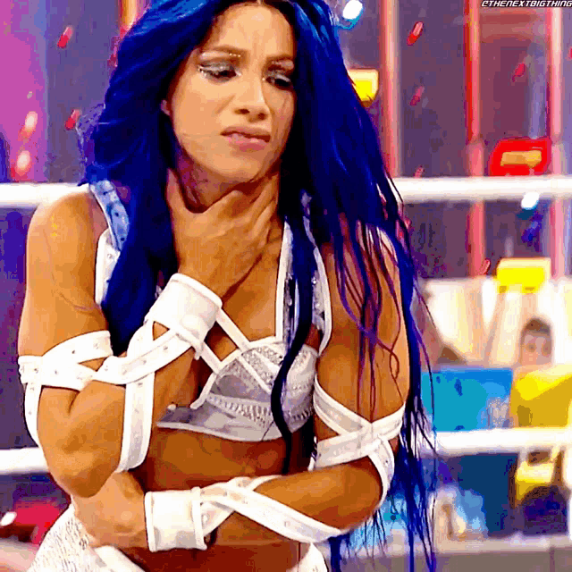 a woman with blue hair is holding her neck in a ring