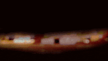 a blurred image of people sitting around a fire with a dark background