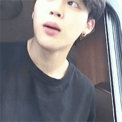 a close up of a young man wearing a black shirt and earrings looking out of a car window .