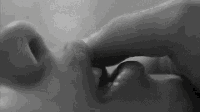 it is a black and white photo of a person licking another person 's tongue .
