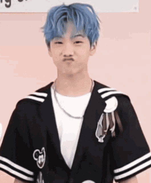 a young man with blue hair is making a funny face while wearing a black jacket .
