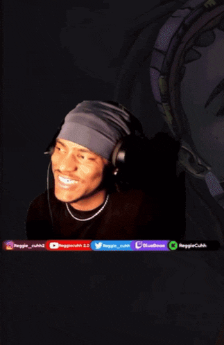 a man wearing headphones and a headband is smiling in front of a sign that says reggie cuhk