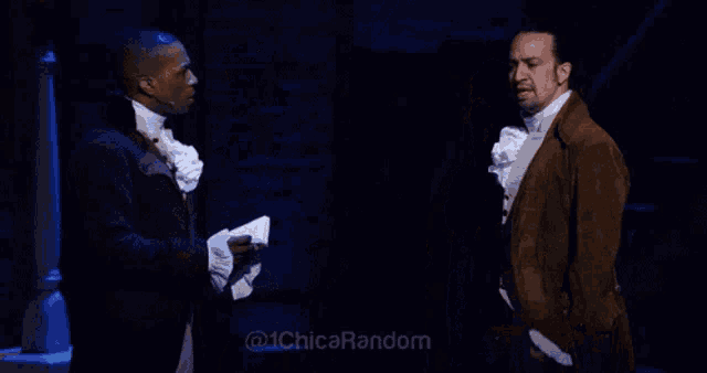two men are standing next to each other on a stage and one is reading a book .