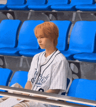 a baseball player wearing a jersey that says ' aloha ' on it sits in a stadium