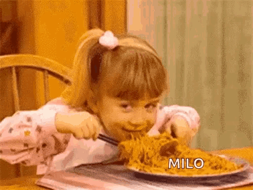 a little girl is eating spaghetti with a fork and knife at a table .