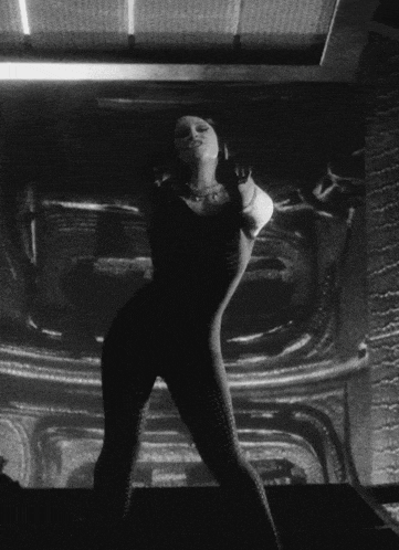 a black and white photo of a woman standing in front of a wall