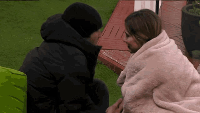 a man and a woman wrapped in a blanket are looking at each other