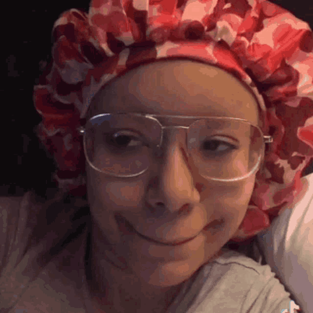 a woman wearing glasses and a red hat smiles for the camera