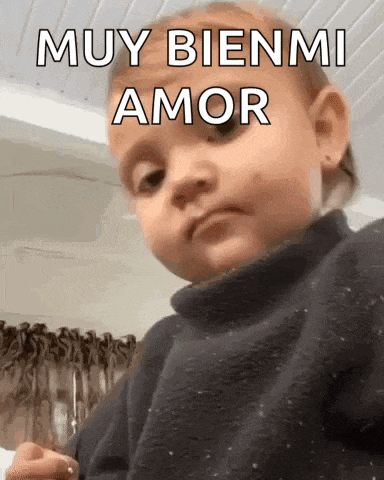 a baby is wearing a black sweater and making a funny face .
