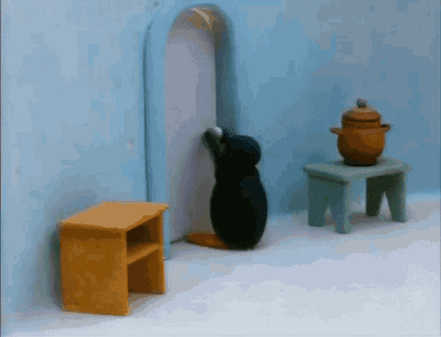 a penguin is standing in a room next to a pot