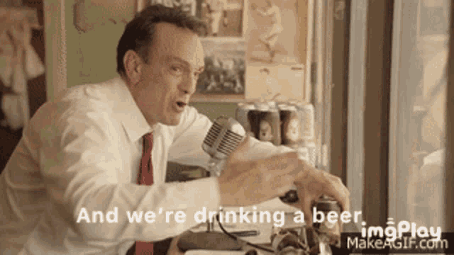 a man talking into a microphone with the words " and we 're drinking a beer "
