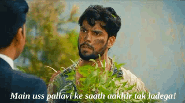 a man with a beard is talking to another man with a plant in front of him .