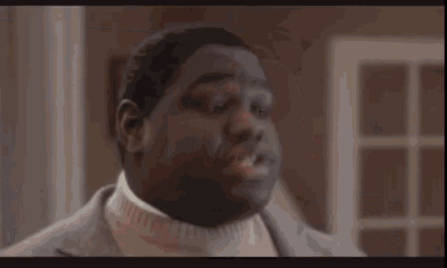 two women are sitting on a couch in a living room . one is holding a gun .