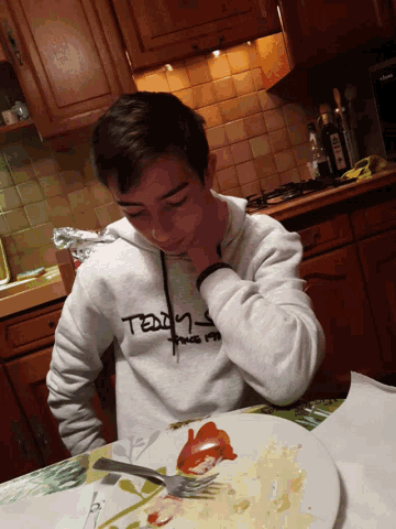 a man wearing a teddy bear sweatshirt is sitting at a table