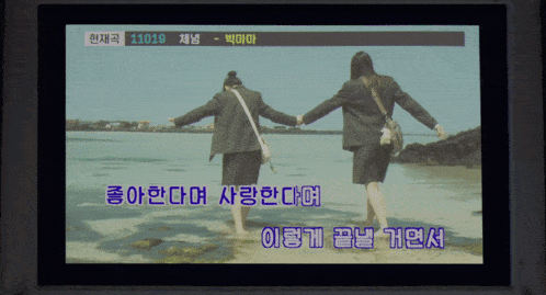 a screen shows two women holding hands on a beach with the number 11019 at the top