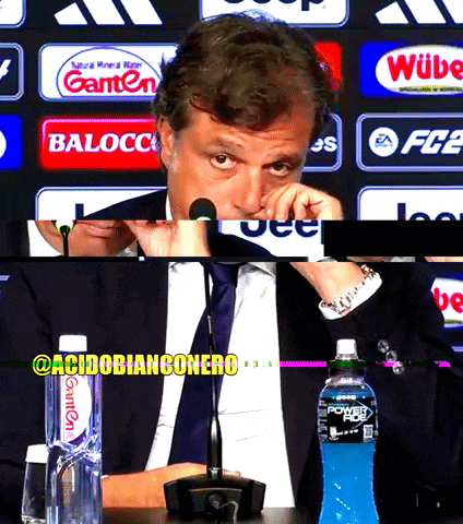 a man sitting in front of a microphone with a bottle of powerade next to him