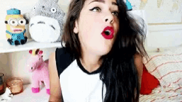 a girl wearing a totoro hat is sitting on a bed with stuffed animals