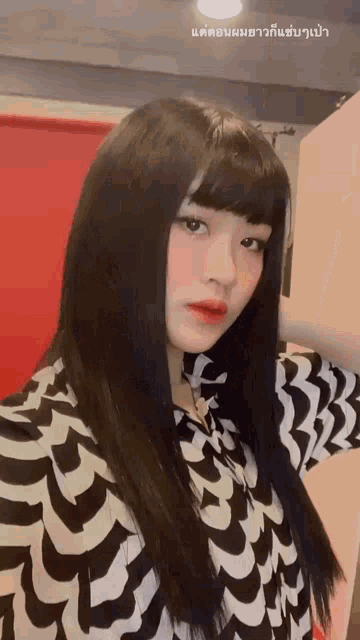 a girl with long black hair and bangs is wearing a black and white shirt .