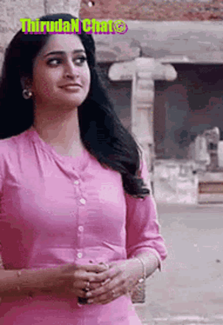 a woman in a pink dress is standing on a street .