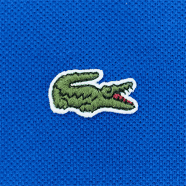 a close up of a lacoste logo on a light green shirt
