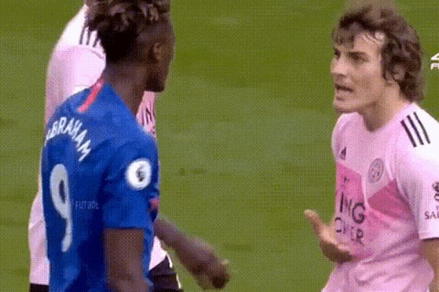 two soccer players are standing next to each other on the field .