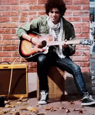 a man is sitting on a box playing a guitar