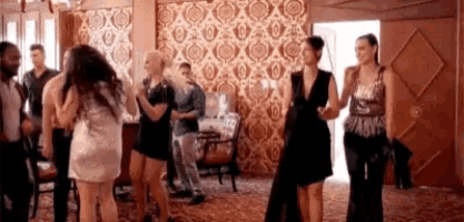 a group of people are dancing in a room with a patterned wall .