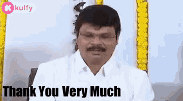 a man wearing glasses and a white shirt is sitting in front of a sign that says `` thank you very much '' .