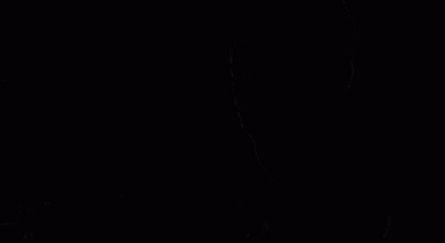 a young man in a hoodie is holding a flashlight in his hand in a dark room .