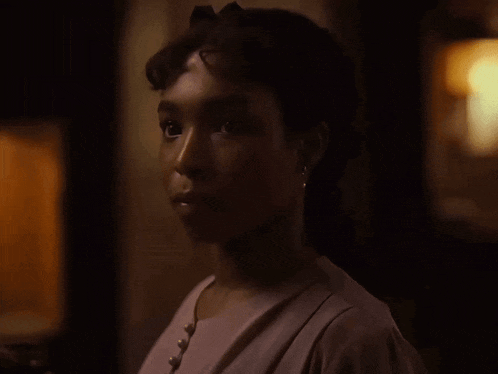 a woman in a purple dress is looking at the camera in the dark .