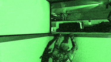 a soldier is climbing up a wall in a video game with a green light behind him .