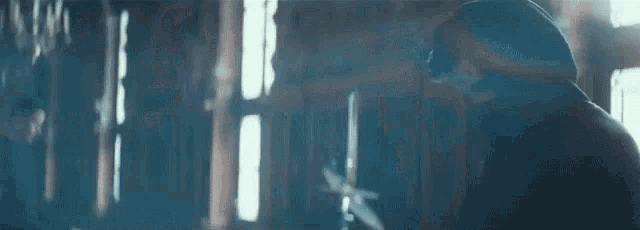a man is standing in front of a window in a dark room with a sword in his hand .