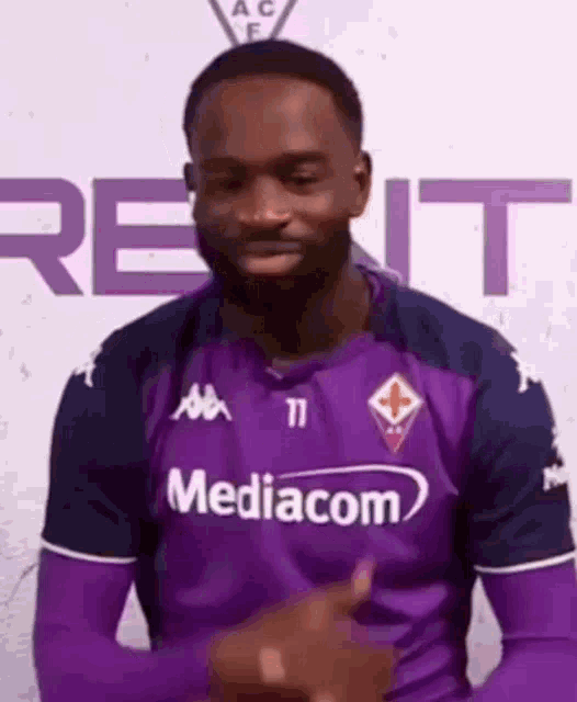 a man in a purple jersey is pointing at the camera .