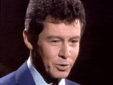 a close up of a man in a suit and tie making a face .