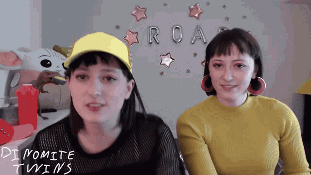 two women sitting in front of a sign that says roar