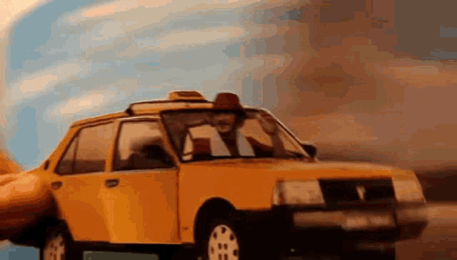 a man in a cowboy hat is driving a toy taxi