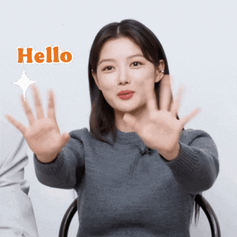 a woman in a grey sweater says hello with her hands out
