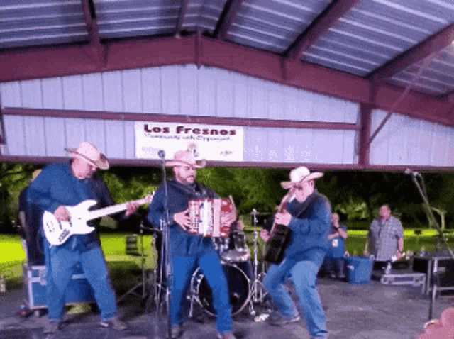 a group of men are playing instruments under a sign that says los fresnos