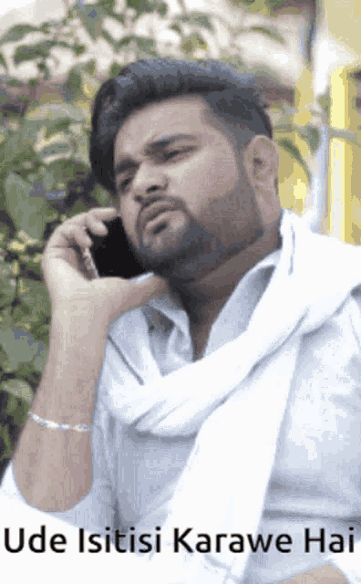 a man with a beard is talking on a cell phone with the words " ude isitisi karawe hai " above him
