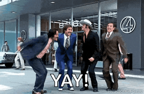 a group of men in suits and ties are dancing in front of a building and saying yay .
