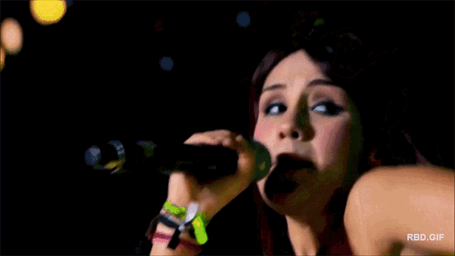 a close up of a woman singing into a microphone with rbd.gif at the bottom
