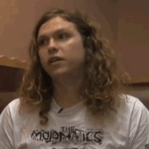 a woman with long curly hair is wearing a white t-shirt with the word mojomatics written on it .