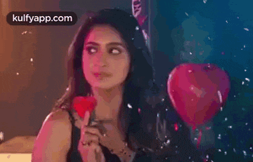a woman is holding a red rose and a heart shaped balloon .